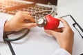 Hands of female doctor holding stethoscope and red heart. Cardiac medical checkup, health care and medical concept