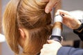 Hands of female hairstylist curls hair client with a curling iron in a hairdressing salon, close up. Royalty Free Stock Photo