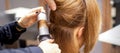 Hands of female hairstylist curls hair client with a curling iron in a hairdressing salon, close up. Royalty Free Stock Photo