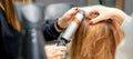 Hands of female hairstylist curls hair client with a curling iron in a hairdressing salon, close up. Royalty Free Stock Photo