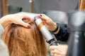 Hands of female hairstylist curls hair client with a curling iron in a hairdressing salon, close up. Royalty Free Stock Photo