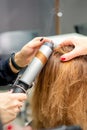 Hands of female hairstylist curls hair client with a curling iron in a hairdressing salon, close up. Royalty Free Stock Photo