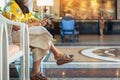 Hands of female traveler wear face mask sit to use smartphone while wait for hotel check in at hotel lobby. Business Woman waiting Royalty Free Stock Photo