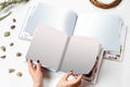 Hands of a female who holding two open photo books with blank pages, green twig and small stones isolated on white Royalty Free Stock Photo