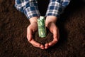 Hands with fertile soil and euro money banknotes