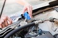 Hands of filling fresh water into the canister of the car windscreen wiper system.