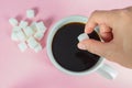 Hands are filling sugar cubes in coffee on a pink background Royalty Free Stock Photo