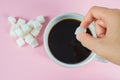 Hands are filling sugar cubes in coffee on a pink background Royalty Free Stock Photo