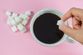 Hands are filling sugar cubes in coffee on a pink background Royalty Free Stock Photo