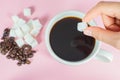 Hands are filling sugar cubes in coffee on a pink background Royalty Free Stock Photo