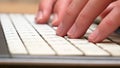 Hands, fingers fast typing on a white laptop keyboard, side view, computer keys extreme closeup, shallow dof. Man working on a Royalty Free Stock Photo