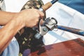 Hands fisherman holding fishing rod and reel handle is rotated Royalty Free Stock Photo