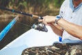 Hands fisherman holding fishing rod and reel handle is rotated Royalty Free Stock Photo