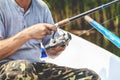 Hands fisherman holding fishing rod and reel handle is rotated Royalty Free Stock Photo