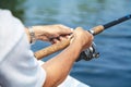 Hands fisherman holding fishing rod and reel handle is rotated Royalty Free Stock Photo