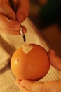 Hands of five years old girl painting yellow heart on blowed easter egg with thin brush