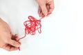 Hands fixing a tangled yarn thread in white background. Problem solving and critical thinking concept.