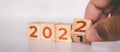 Hands flipping cube wooden block with text year 2022, beginning and trend, calendar and time.