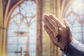 Hands folded in prayer in church with rosary beads and religious cross Royalty Free Stock Photo