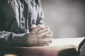 Hands folded in prayer on a Holy Bible in church background, faith, spirtuality and religion Royalty Free Stock Photo