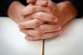 Hands folded in prayer on a Holy Bible in church concept for faith, spirtuality and religion Royalty Free Stock Photo