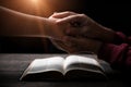 Hands folded in prayer on a Holy Bible in church concept for faith, spirituality and religion, man praying in morning. Man hand