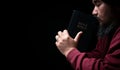 Hands folded in prayer on a Holy Bible in church concept for faith, spirituality and religion, man praying in morning. Man hand