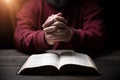 Hands folded in prayer on a Holy Bible in church concept for faith, spirituality and religion, man praying in morning. Man hand