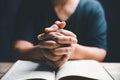 Hands folded in prayer on a Holy Bible in church concept for faith, spirituality and religion, woman praying on holy bible in the Royalty Free Stock Photo