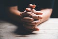 Hands folded in prayer on a Holy Bible in church concept for faith, spirituality and religion, woman praying on holy bible in the Royalty Free Stock Photo