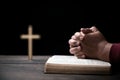 Hands folded in prayer on Holy Bible with cross in church concept for faith, spirituality and religion, Man praying on holy bible Royalty Free Stock Photo