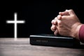 Hands folded in prayer on Holy Bible with cross in church concept for faith, spirituality and religion, Man praying on holy bible Royalty Free Stock Photo