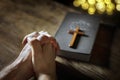 Hands folded in prayer with  Holy Bible and religious crucifix cross in church Royalty Free Stock Photo
