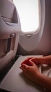 Hands on the folding table of the chair in the cabin of the aircraft near the porthole