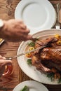 Hands, food and carving the turkey with a senior man using a knife at a dining room table in his home. Chicken Royalty Free Stock Photo