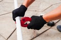 The hands of the foreman hold metal scissors for cutting plastic water pipes outside.