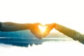 Hands forming a heart shape with the lake on a blurry background during the sunset Royalty Free Stock Photo