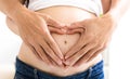 Hands forming the shape of double heart over pregnant belly Royalty Free Stock Photo
