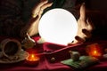 Hands of fortune teller around illuminated crystal ball