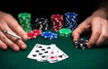 Hands of a gambler closeup and chips on green table in a poker club. A player places a bet on winning poker  three of a kind or Royalty Free Stock Photo