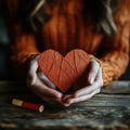Hands holding a textured red heart made of paper with sewing thread on a rustic wooden table Royalty Free Stock Photo