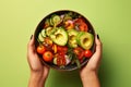 Hands Embrace a Bowl of Nutrient-Packed Salad, Showcasing Sliced Avocado, Tomato, and an Assortment of Fresh Vegetables