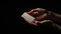 Hands gently hold a small, rectangular piece of paper with serrated edges in a dimly lit setting