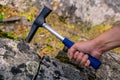 Geologist examines a mineralogical sample with the help of a geological hammer