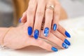 Hands of a girl with a beautiful blue manicure are on display. blue glossy nail