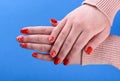 Hands of a girl in a beige sweater with a red manicure on her nails Royalty Free Stock Photo