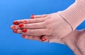 Hands of a girl in a beige sweater with a red manicure on her nails Royalty Free Stock Photo