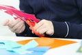 Hands of girl cutting flower from colored paper for crafts Royalty Free Stock Photo