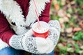 Hands of girl holding cup of hot drink and sitting on grass Royalty Free Stock Photo