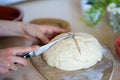 Hands of a girl holding knife and making cross on easy to prepare and healthy, home made irish soda bread - during stay at home Royalty Free Stock Photo